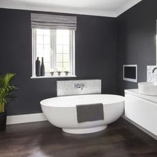 grey walled bathroom with bathtub and potted plant