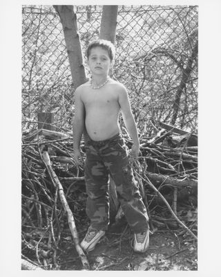 a still from beth garrabrant's things shouldn't be so hard of a boy named louis standing outside by sticks in camo pants