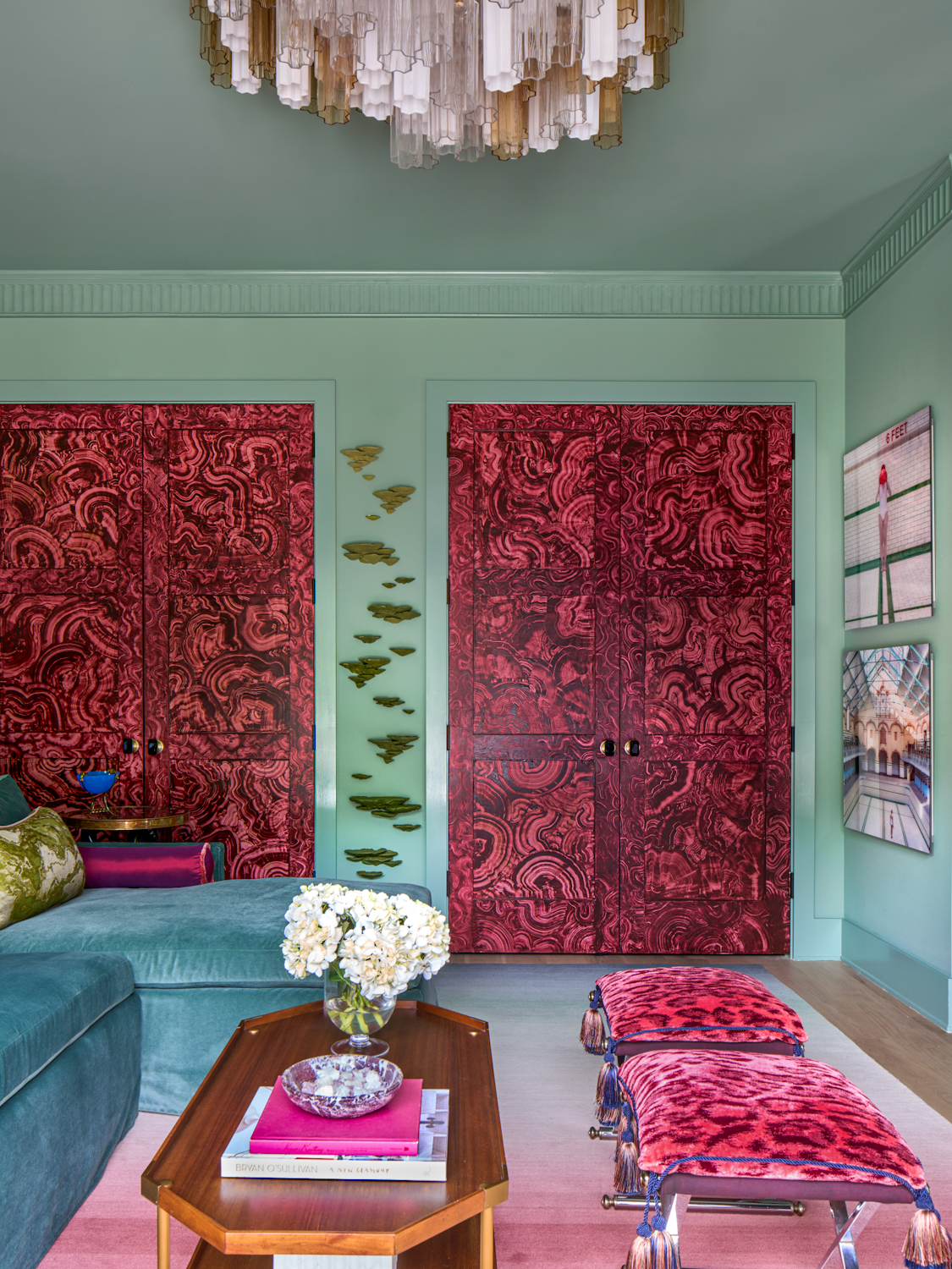 A living room with teal walls, imitation &#039;jewel&#039; doors, and a blue sofa