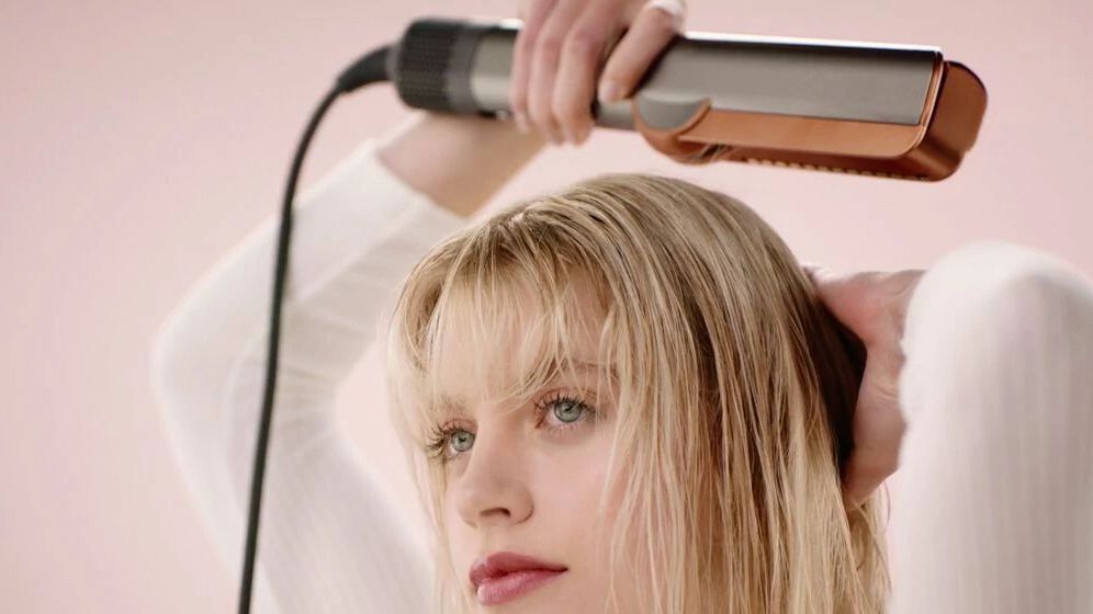 Woman holding the Dyson Airstrait above her head