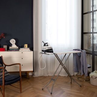 Ironing board with iron next to chair and console table
