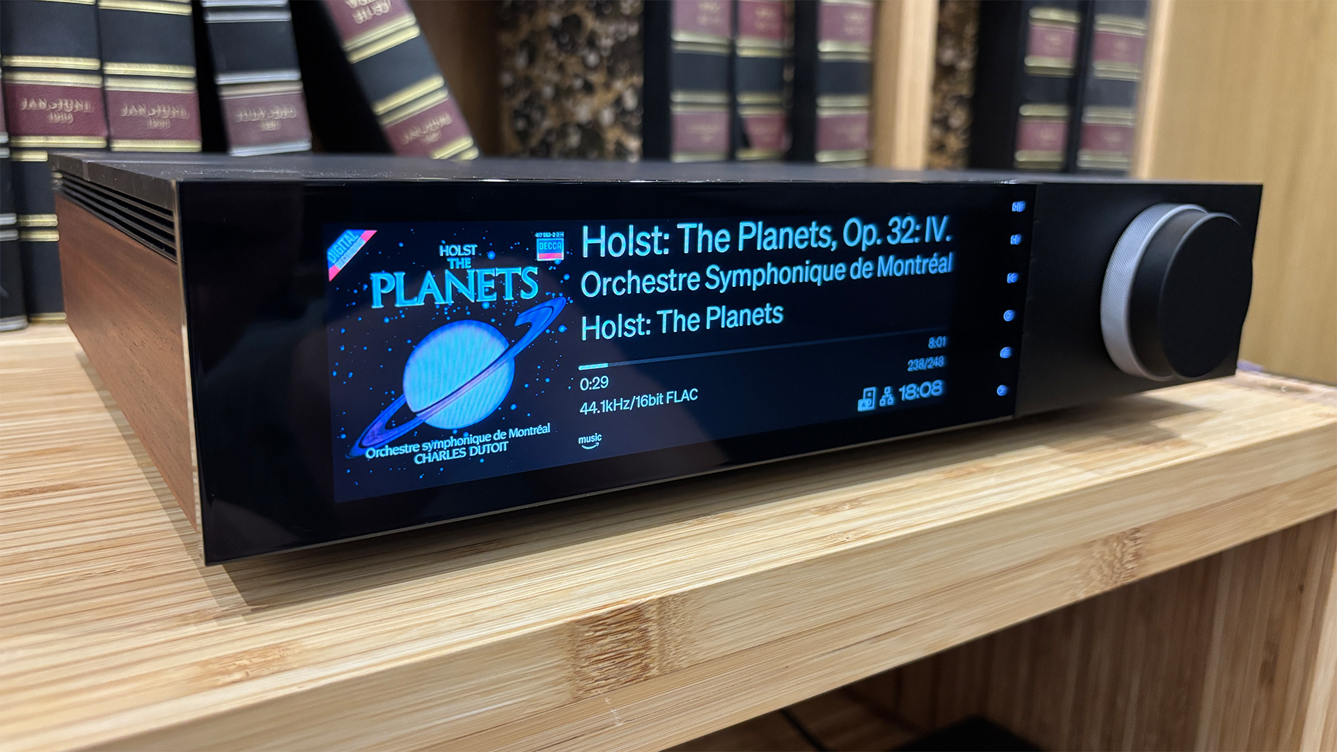 Cambridge Audio Evo 300 all-in-one system on wooden hi-fi rack in front of bookcase, on display is Holst: The Planets