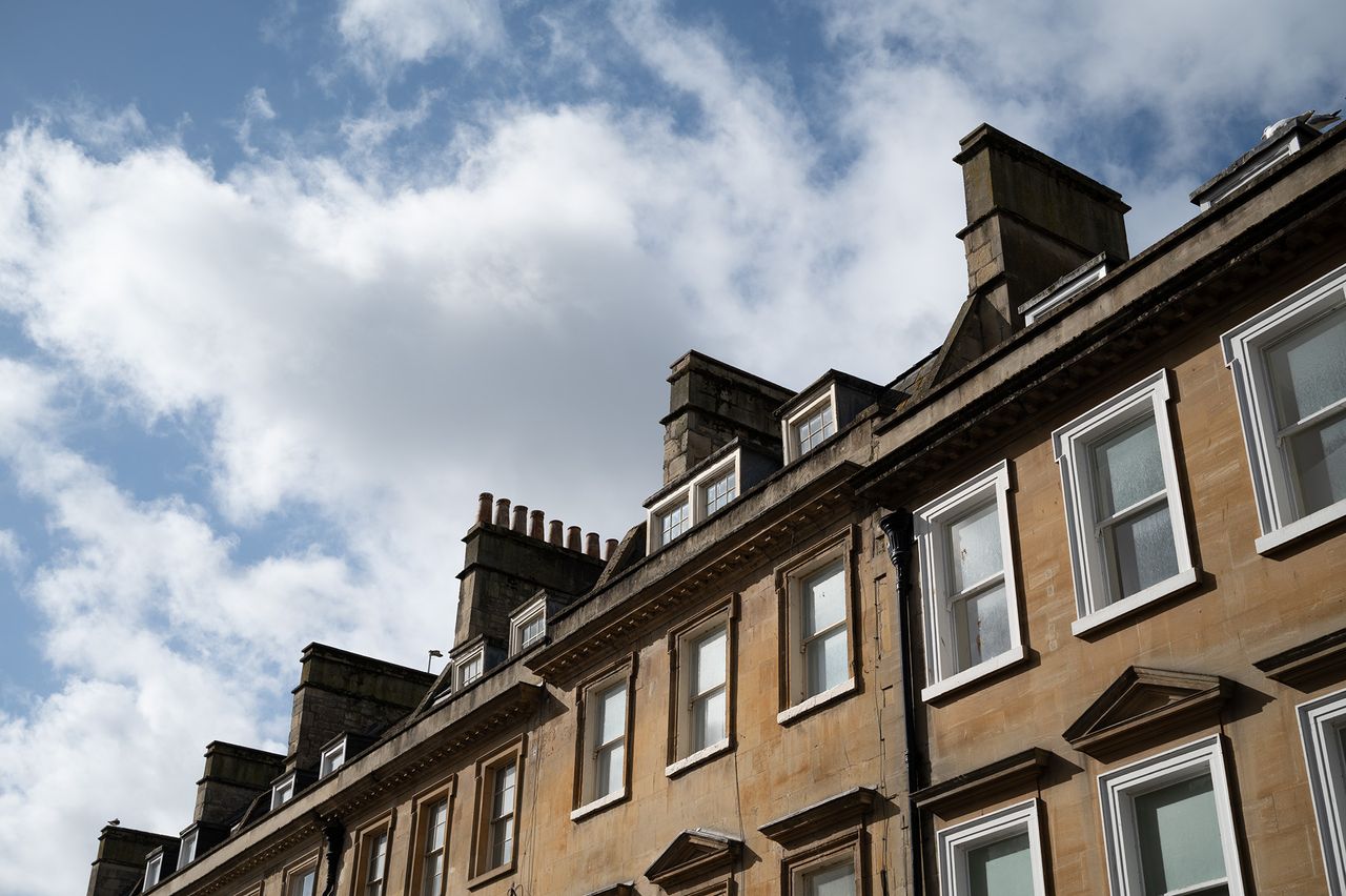 The tops of a row of a Georgian terrace in the City of Bath against a blue sky