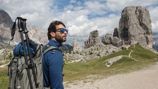 Hiker wearing sunglasses and carrying trekking poles