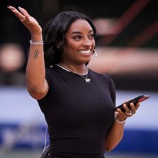 a black woman with short hair wearing a black shirt and waving at a crowd
