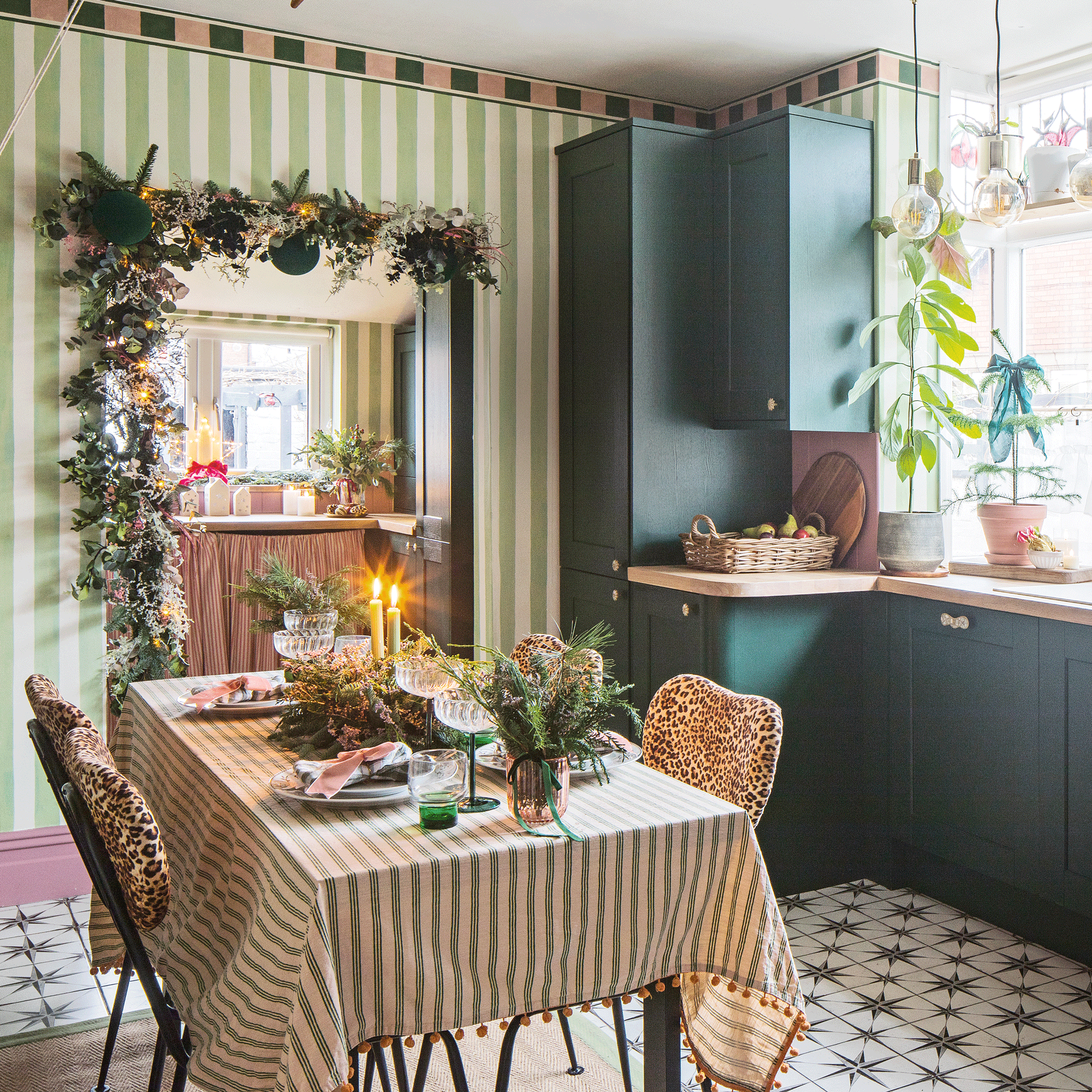 a kitchen diner with green cabinetry, green and white striped wallpaper, a dining table with a matching tablecloth and dining chairs upholstered in leopard print fabric