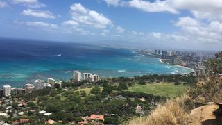 A photo of the Honolulu beaches next to a city and green island landscape