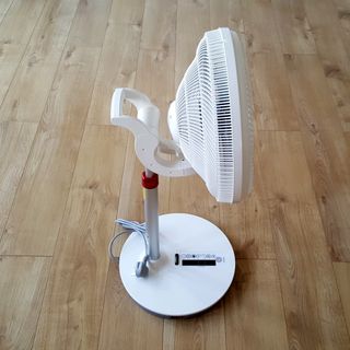 The white pedestal EcoAir Kinetic fan being unboxed and assembled on a wooden floor