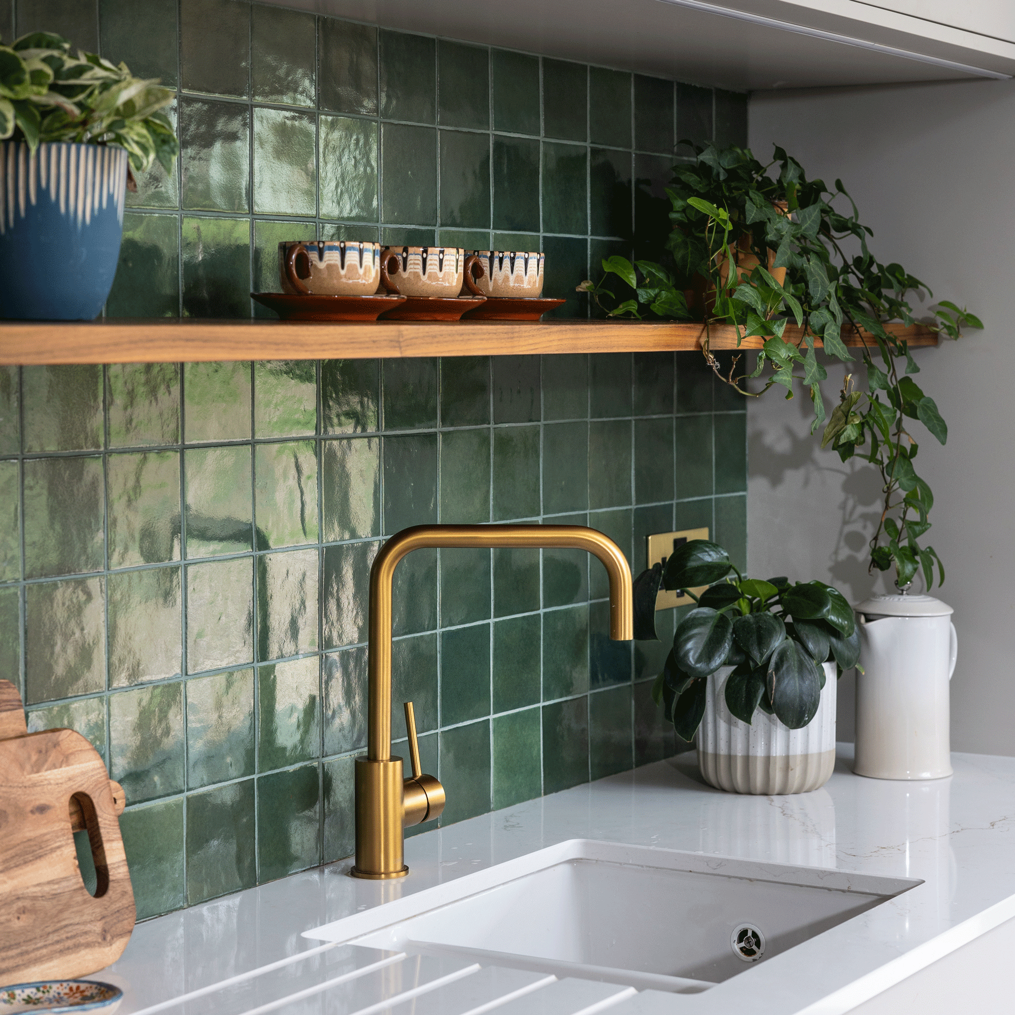 a kitchen with a green tiled splashback and white countertop and sink