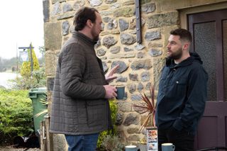 Liam confronts Aaron in Emmerdale while holding a cup of drink