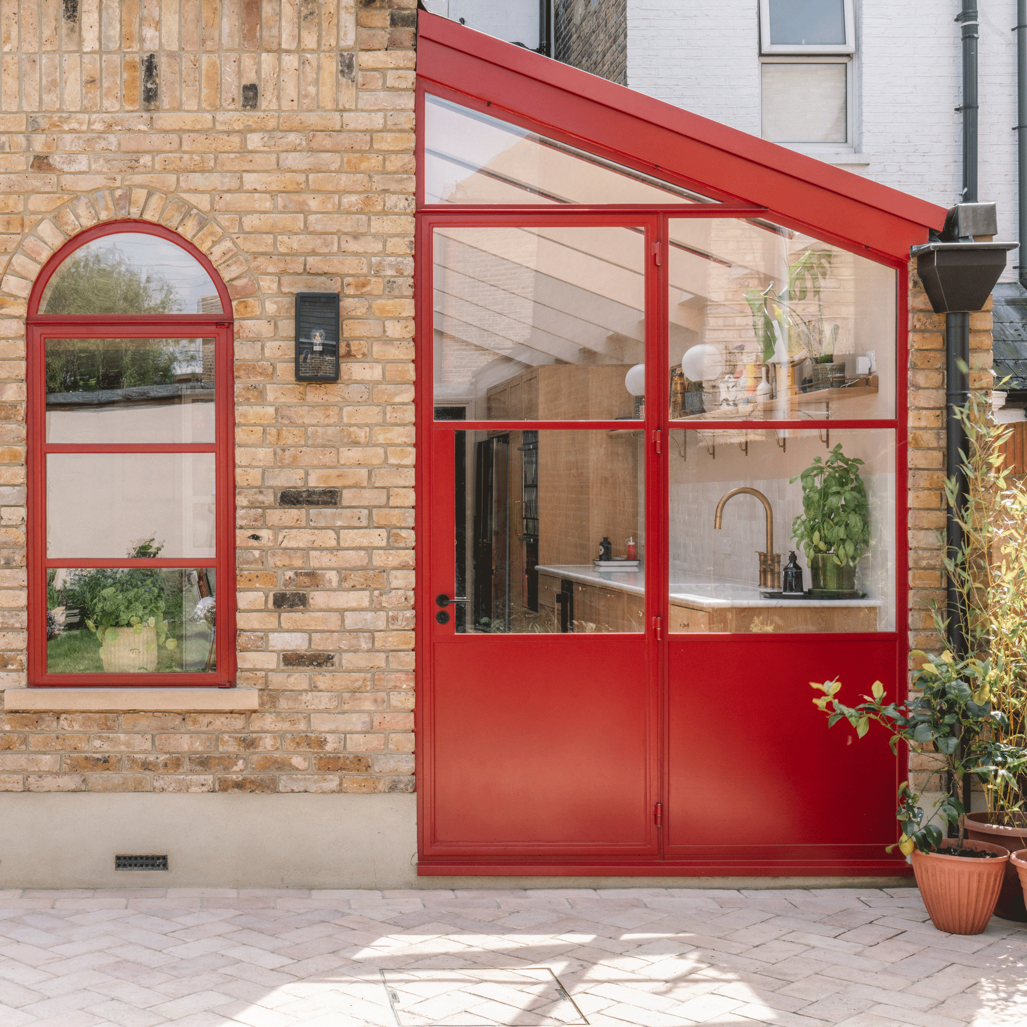exterior view of a side return extension kitchen with red patio doors skylight and matching arched windows