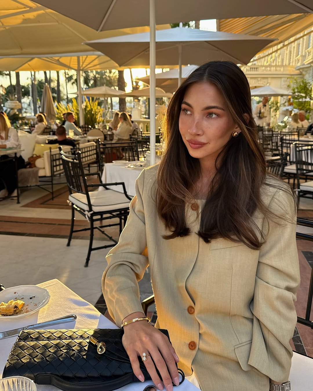 @fakerstrom wears a light beige collarless blazer with white jeans and a woven leather clutch