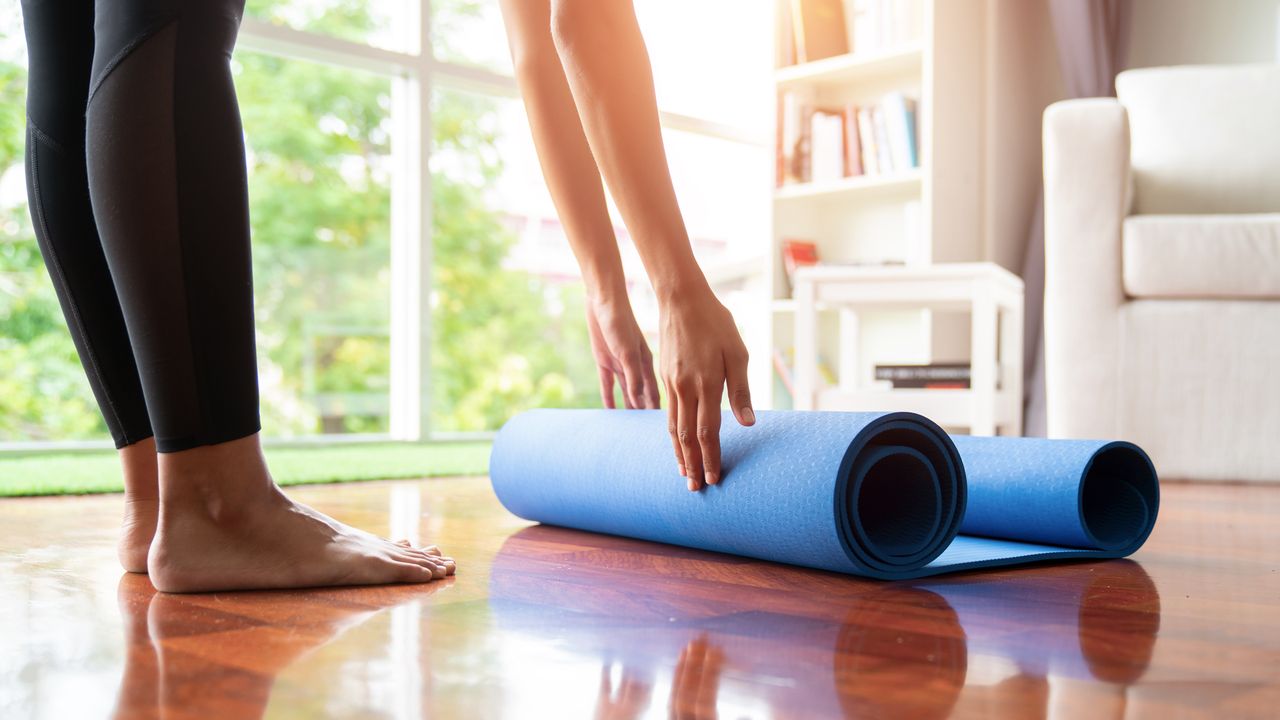 Person rolls up a yoga mat on the floor