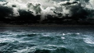 An image of an open oceans surface with crashing waves and a stormy sky.