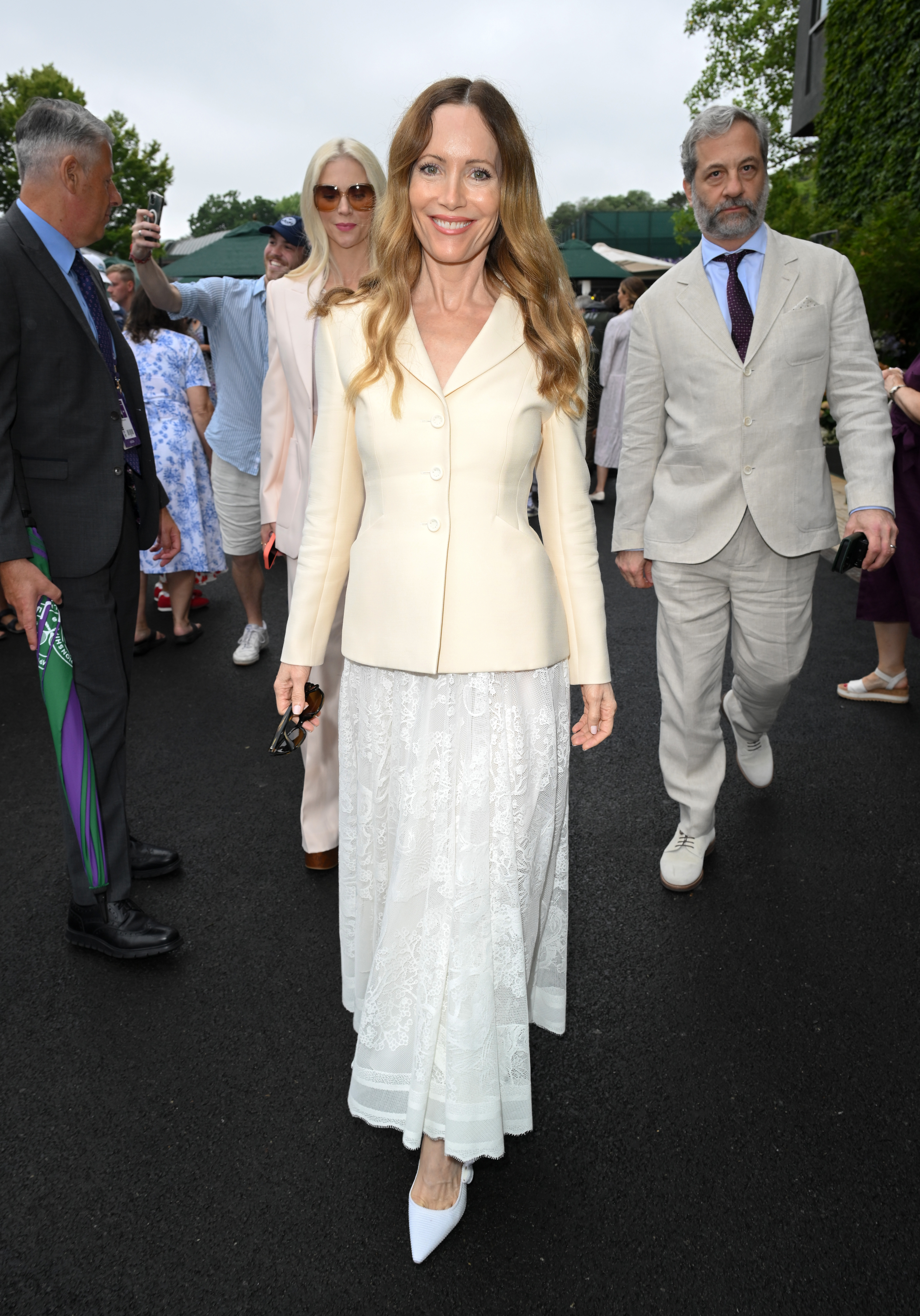 Lesley Mann wears a cream blazer and white lace skirt with a pair of white pointed toe shoes