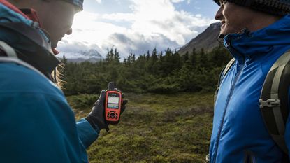 Best hiking GPS: Two hikers looking at a handheld hiking GPS