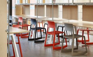 Desks with coloured plastic chair in a classroom style with pin boards in front of each desk