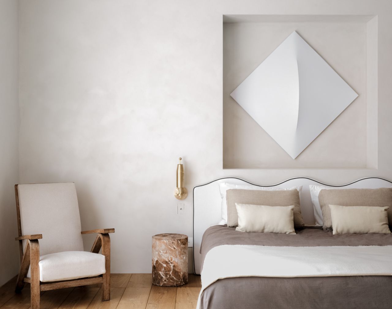 A white toned bedroom with wall decor above the bed