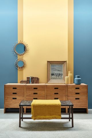 wooden sideboard with blue walls and yellow strip of paint in the centre