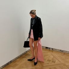 Eliza Huber wearing a black leather blazer, pink miniskirt, and gray shrunken cashmere J.Crew sweater with black heels.