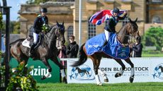 Bronze medallists JL Dublin ridden by Tom McEwen (left) and individual gold medalist Laura Collett holds the union flag aloft on board London 52, who is wearing his winners rug on their lap of honour in front of Blenheim Palace.
