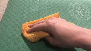 A yoga mat being cleaned with a microfiber cloth