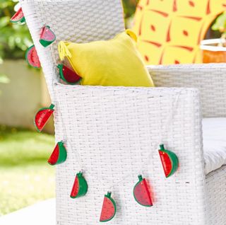 white chair with yellow pillow and watermelon lighting cord