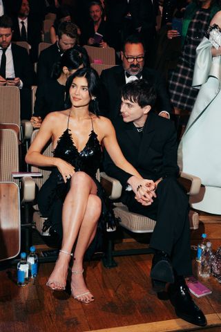 A photo of Kylie Jenner holding hands with Timothée Chalamet in a backless black sequin dress.