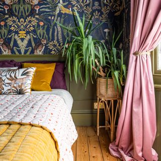 bedroom curtain mistakes, colourful bedroom with wood themed wallpaper, yellow bedspread, pink curtains with hold backs, plant, wooden floorboards, green painted panelling and woodwork