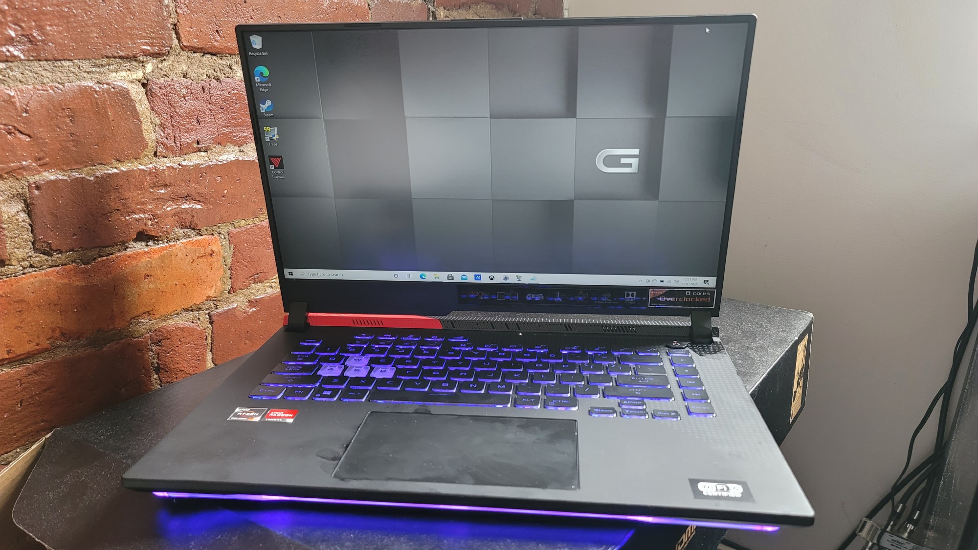 Asus ROG Strix G15 Advantage Edition on a desk with purple RGB lighting