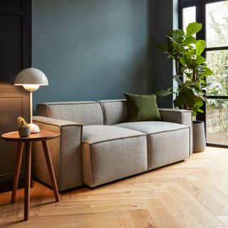Swyft grey sofa with side table and lamp, wooden floor, and plant to the right