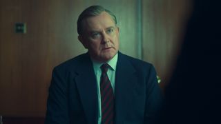 Boyce sits looking sternly in The Gold season 2