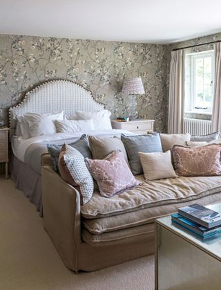 double bedroom with floral wallpaper and sofa with cushions