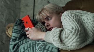 A woman looks at her phone in despair