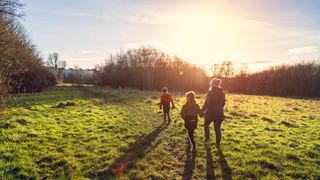 A woman and two children take an early morning walk in winter sunshine