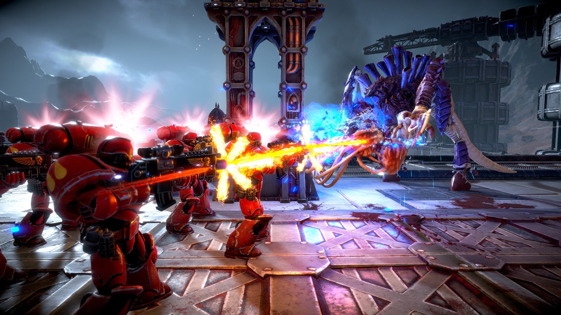 Red-armored sci-fi soldiers fire glowing weapons at a towering blue, spiked alien creature in a ruined industrial arena, amid explosive light and chaos.