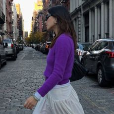 Influencer @vivianyrl wears a purple knit with a white skirt and red socks.