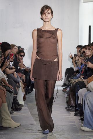 Paloma Wool model wearing a sheer brown top and skirt-over-pants look at the spring/summer 2024 show.