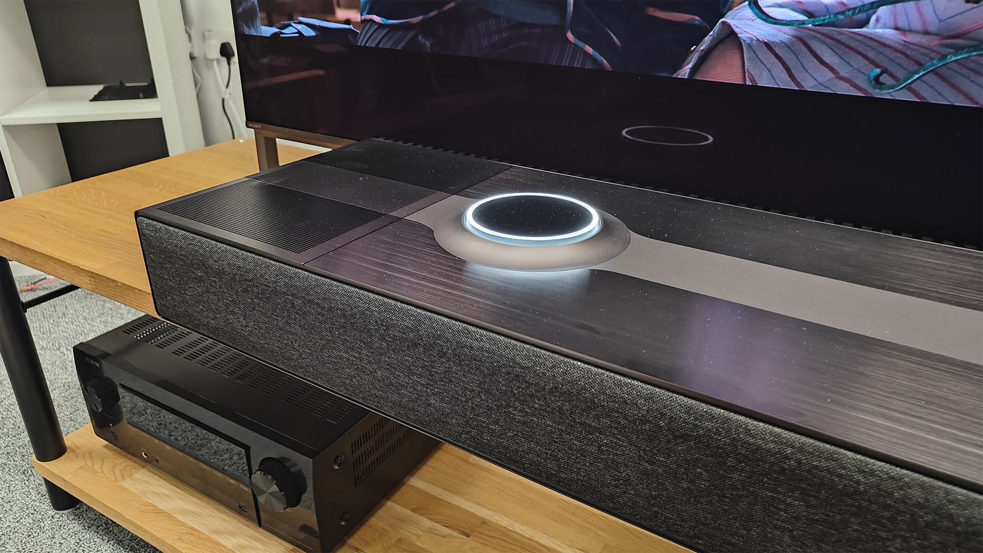 Focal Mu-so Hekla soundbar on wooden AV rack in front of TV