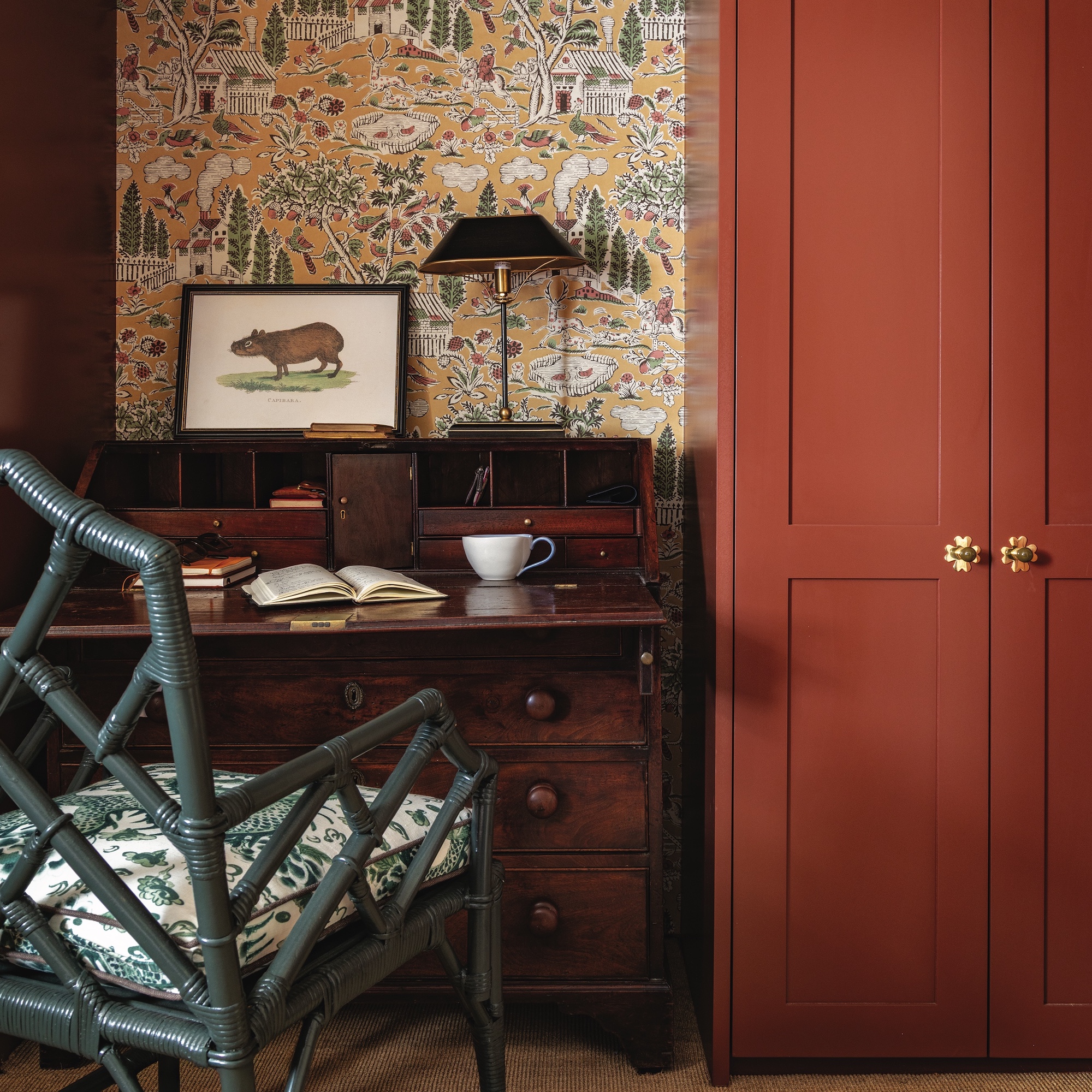 small study area with antique wooden desk and bamboo chair next to fitted cabinet