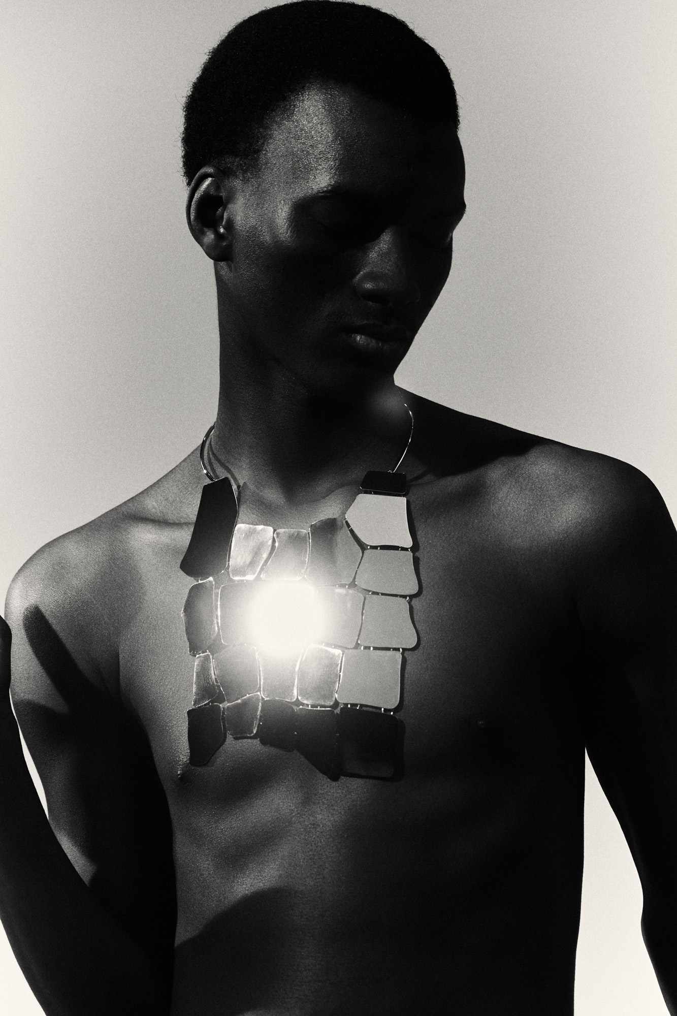 Close up on man in black and white wearing Celine chest-covering metallic necklace