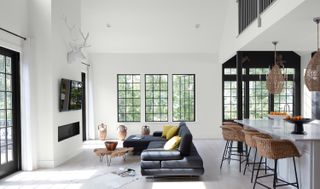 A whitw living room with black sofa and window frames
