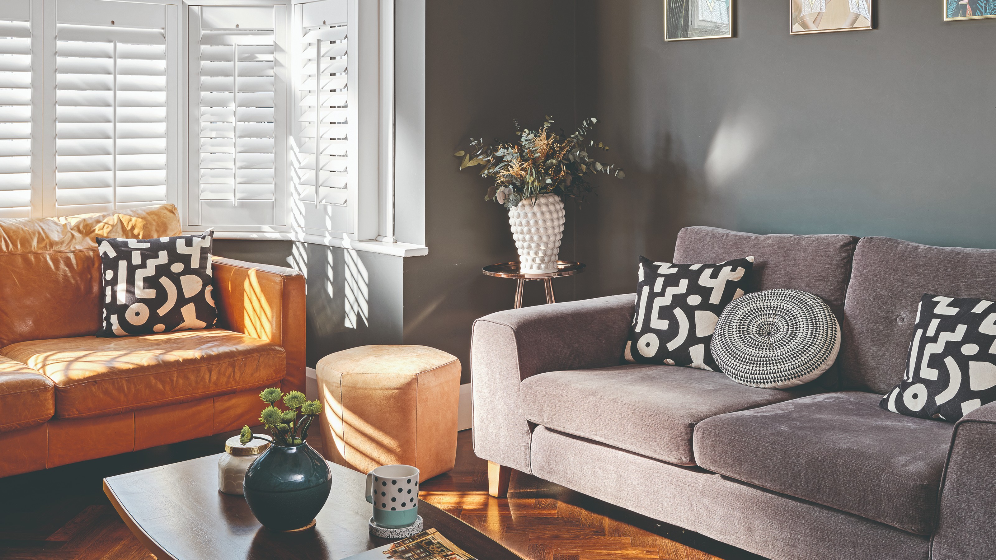 A dark grey-painted living room with a grey sofa and a light brown leather sofa