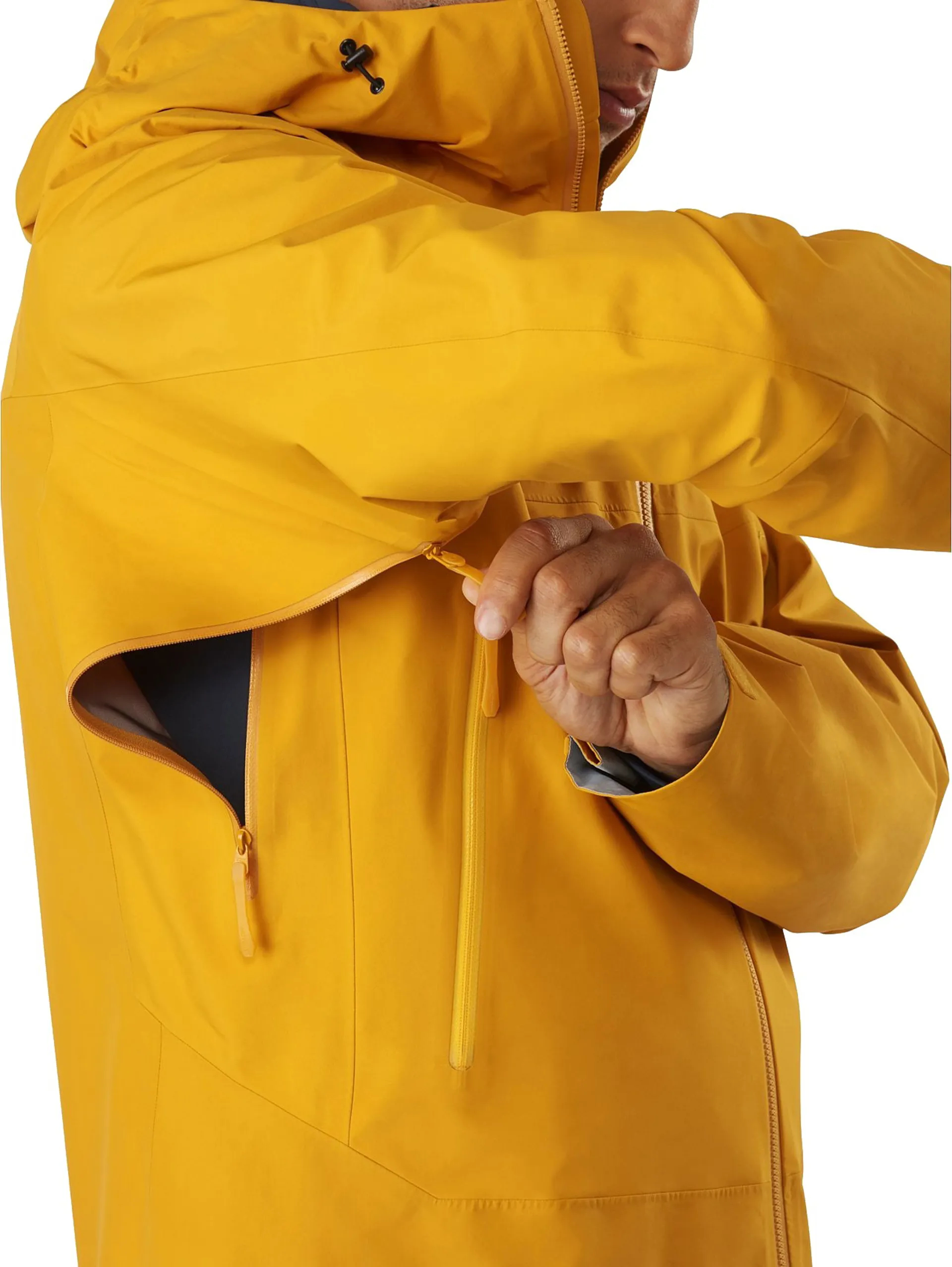 A man unzips the pit zips on a bright yellow waterproof jacket