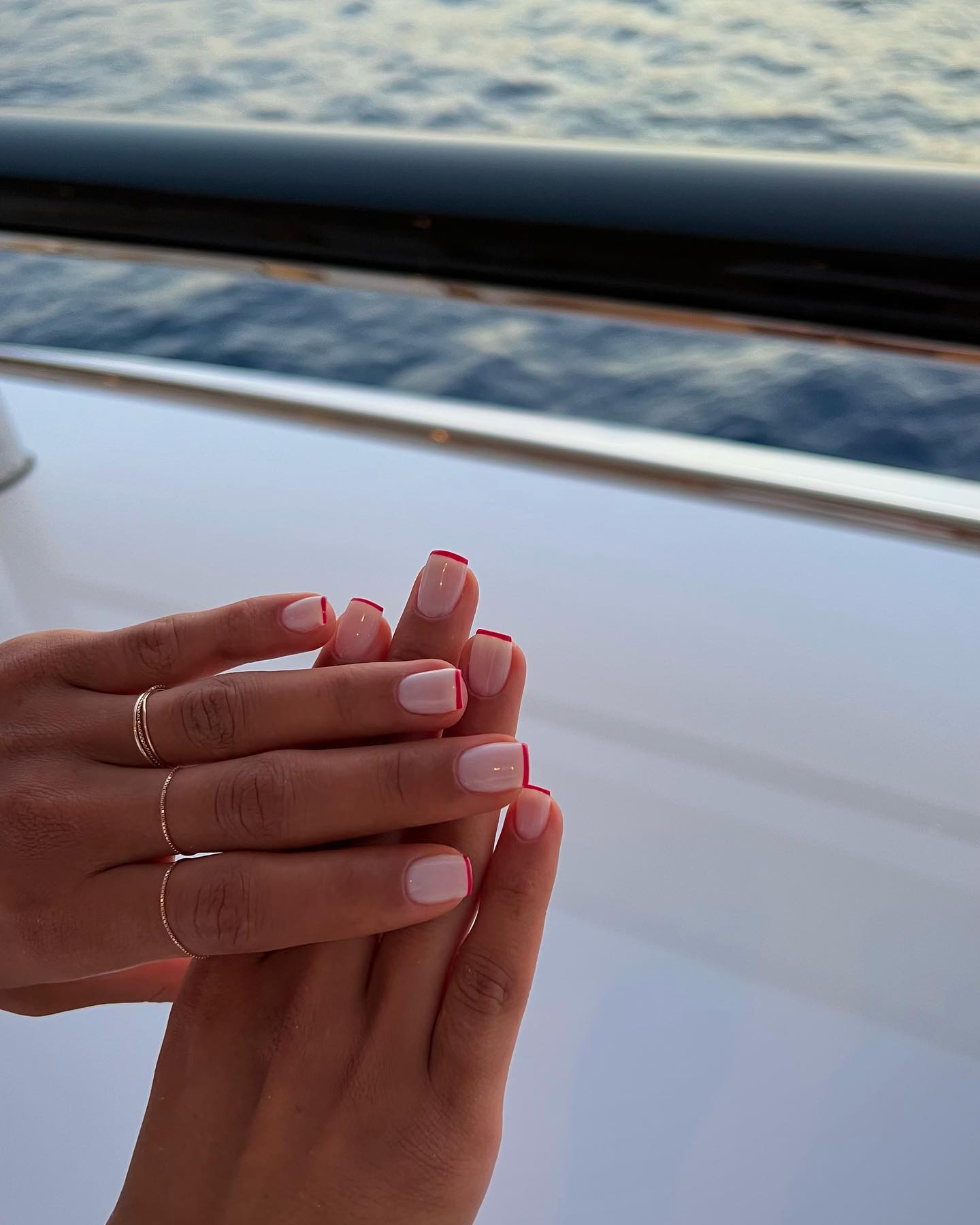 Photo of a red French manicure in front of the ocean