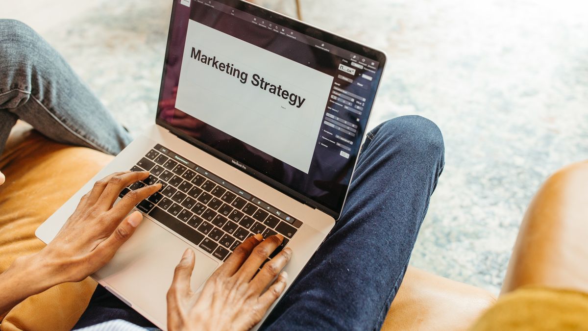 Man sit with laptop document open which reads Marketing Strategy