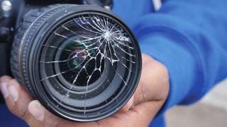 Man holding broken DSLR camera lens; Shutterstock ID 286091423