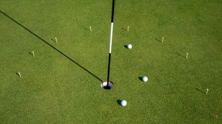A semi-circle of tees and three golf balls on the 13th green at Royal Troon
