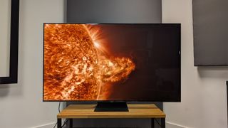 TCL C855K 65-inch Mini LED TV on wooden AV bench with solar flare on screen