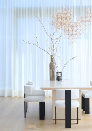 Dining area with square block travertine table and black and white dining chairs